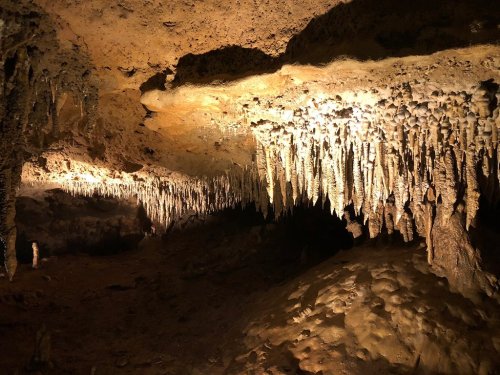 Stalactites and stalagmites in a dimly lit cave, showcasing unique rock formations and textures.