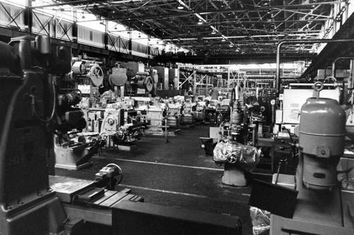 A black and white photo of a large industrial workshop filled with various machines and equipment.
