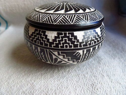 A round, intricately designed pottery jar with black and white geometric patterns and a fitted lid.