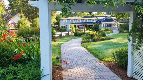 A scenic pathway leads through lush gardens to a charming building, framed by greenery and colorful flowers.