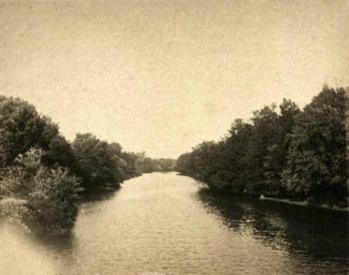 A serene river scene surrounded by lush trees, captured in a vintage style.