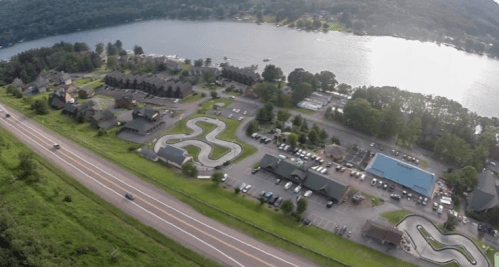Aerial view of a lakeside resort with winding roads, parking lots, and recreational areas near a body of water.