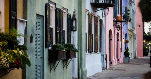 Colorful buildings with decorative windows and flower boxes line a charming street, creating a picturesque scene.