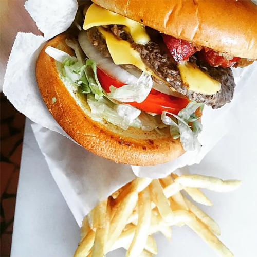 A juicy cheeseburger with lettuce, tomato, and bacon, served with a side of golden French fries.