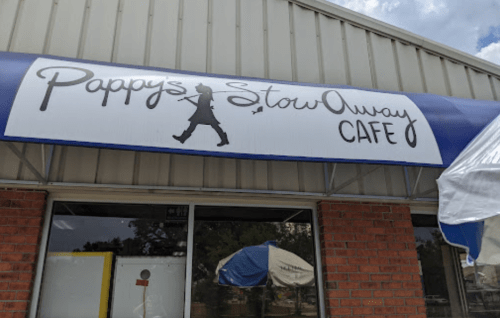 Sign for "Pappy's Stow Away Cafe" featuring a silhouette of a person walking. Building exterior with brick and awning.