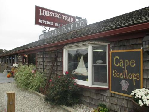 Exterior of The Lobster Trap Co. restaurant, featuring a sign and a chalkboard advertising "Cape Scallops."