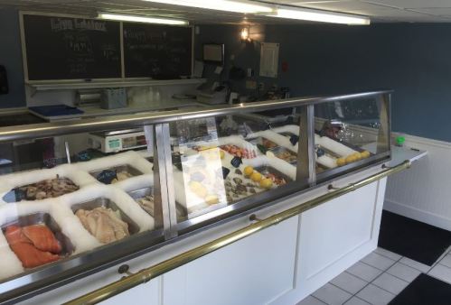 A seafood market display featuring various fresh fish and shellfish in a clean, well-lit environment.
