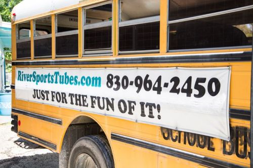 A yellow school bus with a banner advertising RiverSportsTubes.com and a phone number for fun activities.