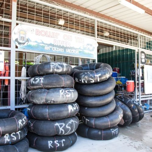 A stack of black inner tubes outside a saloon, with a sign reading "Rollin' on the River."