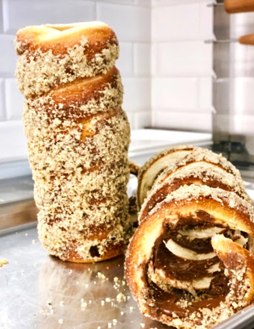 Two spiral pastries coated in a crumbly topping, one stacked upright and the other lying on its side, on a metal surface.
