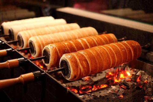 Golden-brown pastries roasting on skewers over glowing embers, creating a delicious, crispy exterior.