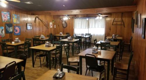 A rustic dining room with wooden walls, empty tables, and artwork, featuring a cozy, inviting atmosphere.