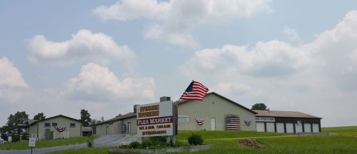 A large building with a sign for "Southern Pennsylvania Flea Market," featuring an American flag and bunting.