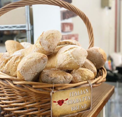 A basket filled with freshly baked Italian ciabatta bread, labeled with a sign.