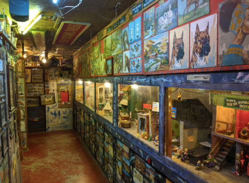 A colorful hallway filled with framed artwork and display cases showcasing miniature scenes and collectibles.