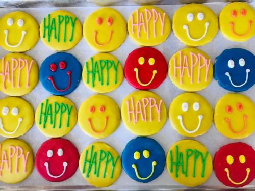 A tray of colorful cookies featuring smiley faces and the word "HAPPY" in various bright colors.