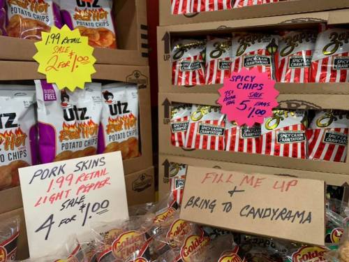 Display of snack bags including potato chips and pork skins, with sale signs indicating prices and promotions.