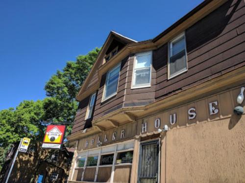 A brown two-story building with "Holler House" sign, surrounded by trees and a clear blue sky.