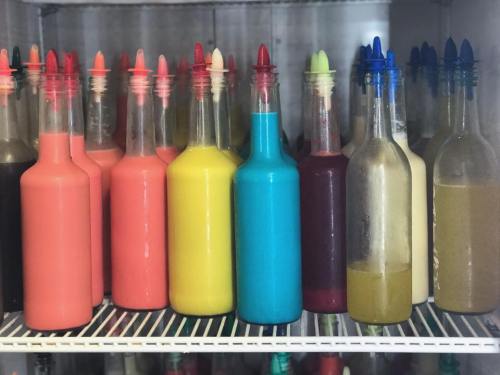 A variety of colorful bottles filled with different liquids, arranged neatly on a shelf.