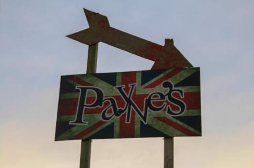Sign for "Pax's" featuring a British flag design and an arrow pointing to the right.