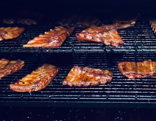 Smoky barbecue ribs arranged on a grill, showcasing a variety of cuts and a rich, caramelized glaze.
