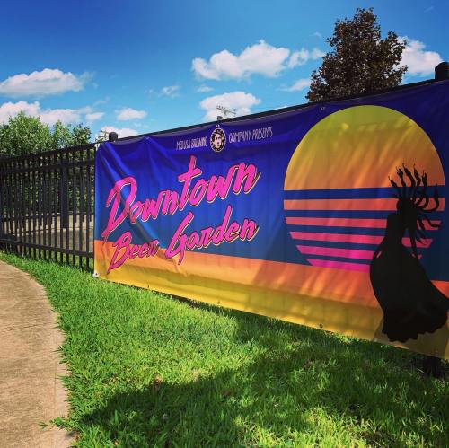 A colorful banner for "Downtown Beer Garden" featuring a sunset and a silhouette of a dancer against a blue sky.