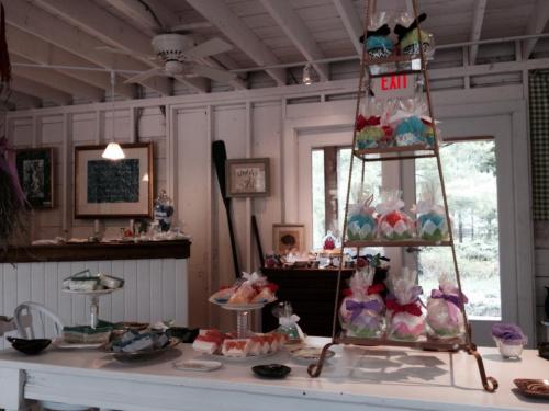 A cozy shop interior featuring a tiered display of colorful wrapped treats and a table with assorted sweets.