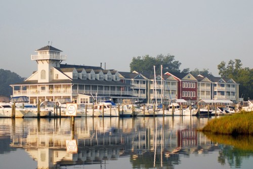 A serene marina scene with boats docked in front of a charming waterfront hotel, reflecting in calm waters.