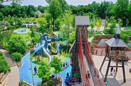 Aerial view of a vibrant park featuring playgrounds, slides, and green spaces with families enjoying the outdoors.