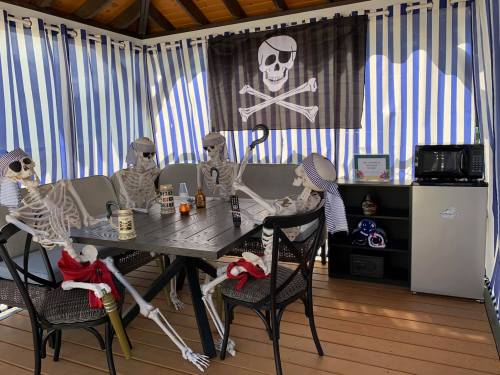 A pirate-themed setup with skeletons sitting around a table, decorated with a skull flag and a small kitchen area.