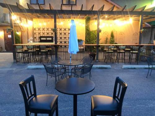 A cozy outdoor dining area with string lights, a bar, and empty tables and chairs in the evening.