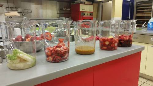 Five clear containers filled with various fruits and sauces, arranged on a kitchen countertop.