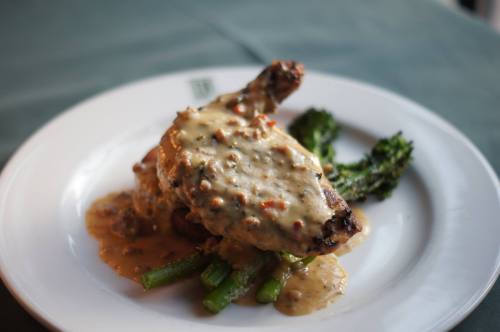 A plate featuring a chicken leg covered in creamy sauce, served with asparagus and a side of broccoli.