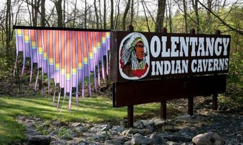 Sign for Olentangy Indian Caverns featuring a colorful design and a Native American chief illustration.