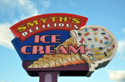 Colorful sign for "Smyth's Delicious Ice Cream" featuring an ice cream cone with sprinkles against a blue sky.
