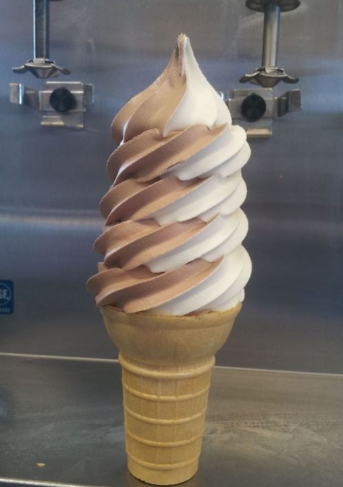 A soft-serve ice cream cone with swirls of chocolate and vanilla, served in a classic waffle cone.
