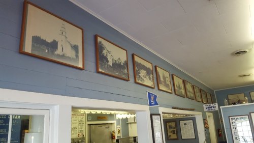 A series of framed historical photographs displayed on a blue wall above a counter in a casual setting.