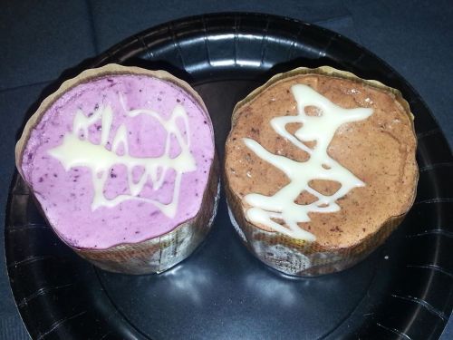 Two dessert cups on a black plate: one purple with a white design, the other brown with a white pattern.