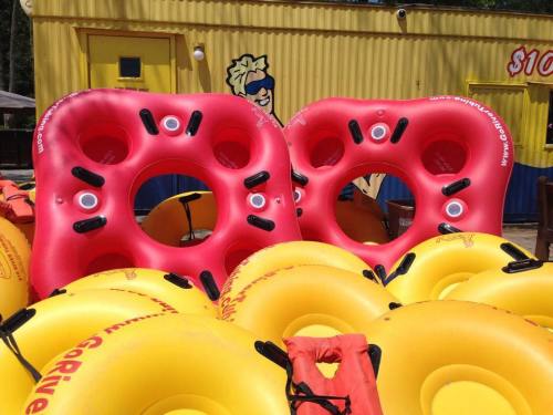 A pile of colorful inflatable tubes, red and yellow, stacked together near a bright yellow building.