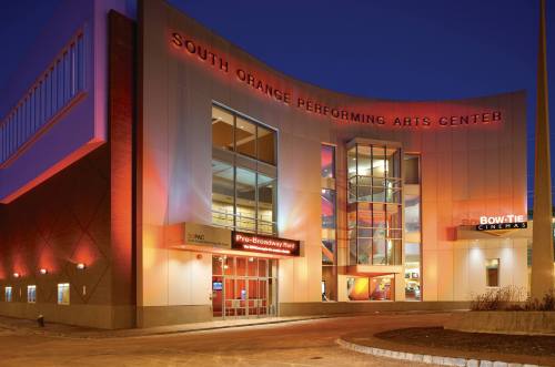 Exterior of the South Orange Performing Arts Center at dusk, featuring modern architecture and illuminated signage.
