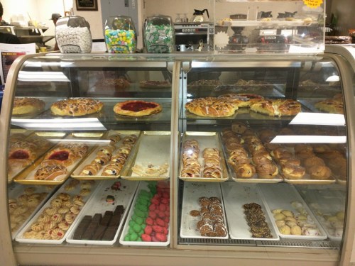 A display case filled with various pastries, including danishes, cookies, and colorful candies.