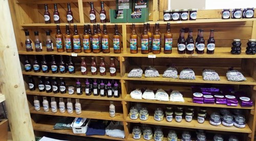Shelves filled with various bottles and jars of sauces, jams, and other products in a rustic wooden display.