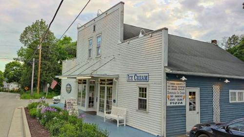 A quaint ice cream shop with a blue and white exterior, featuring a sign that says "Ice Cream" and a bench outside.