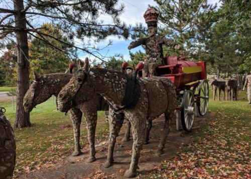 A whimsical sculpture of a horse-drawn carriage made from stones, featuring a figure in a crown atop the carriage.