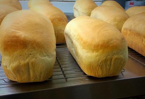 Freshly baked loaves of bread cooling on a wire rack in a bakery.