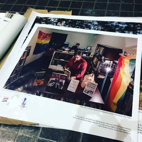 A person reads in a library adorned with rainbow flags and LGBTQ+ books, highlighting a welcoming space.