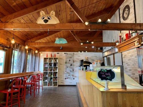 Cozy café interior with wooden beams, red chairs, and whimsical decor, featuring an ice cream counter and shelves.