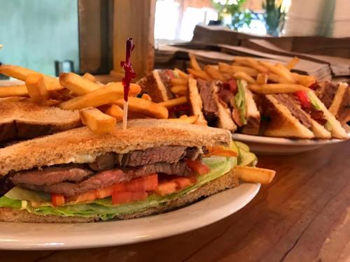 A close-up of a hearty sandwich with lettuce, tomato, and beef, served with a side of crispy French fries.