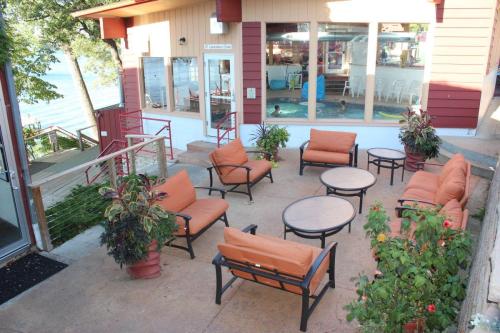 Outdoor seating area with orange chairs and tables, overlooking a pool and lake, surrounded by greenery.