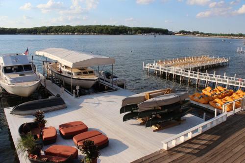 A scenic waterfront view featuring boats, a dock, and paddle boats, with seating areas and trees in the background.